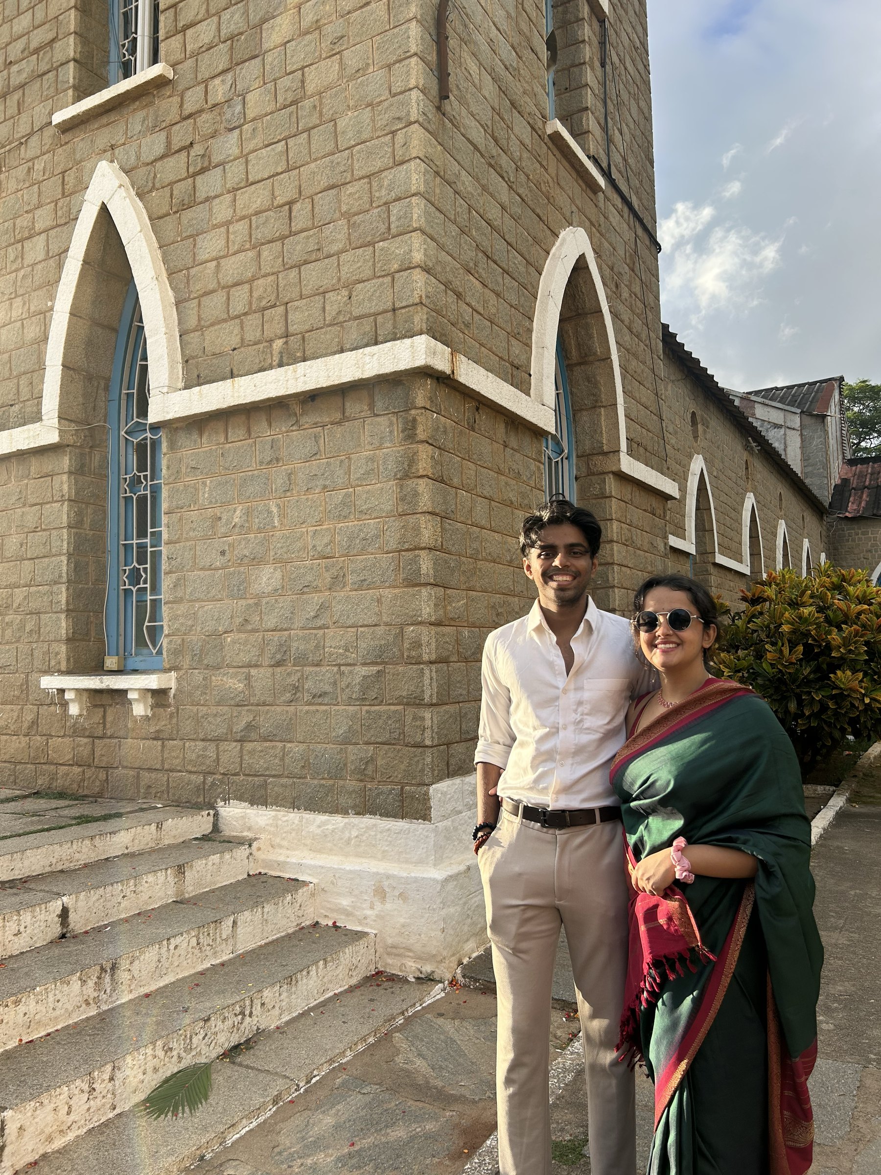 Suraj and Shruti standing together outside a stone church